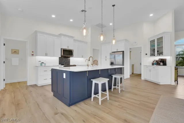 a large kitchen with cabinets chairs and wooden floor