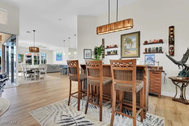 a view of a dining room and livingroom with furniture wooden floor a rug a painting and a chandelier