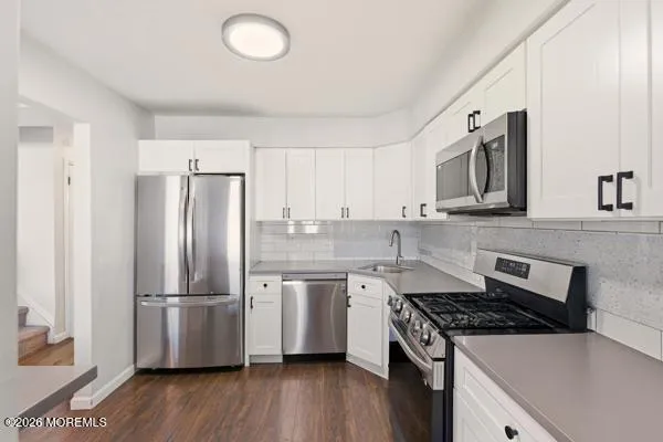 a kitchen with stainless steel appliances a refrigerator a sink and wooden floors