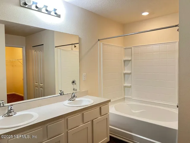 a bathroom with a sink double vanity granite tub shower and a mirror