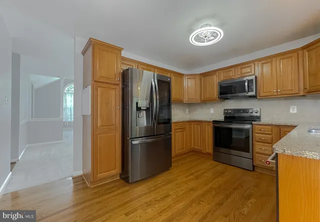 a kitchen with granite countertop a refrigerator and a stove top oven