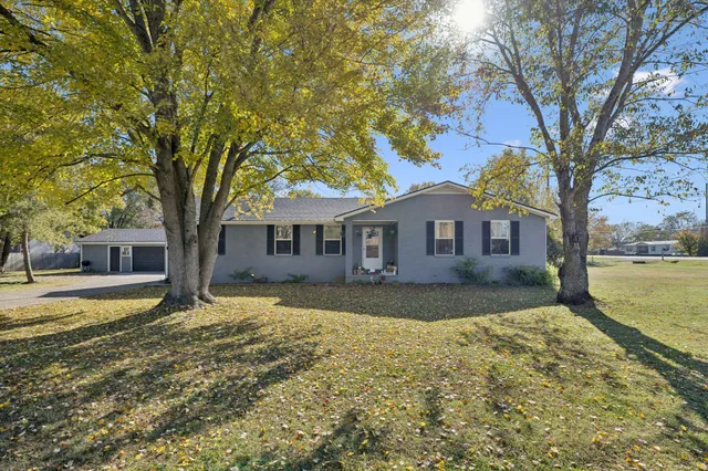 a front view of a house with a yard and large trees