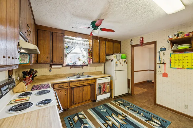 a kitchen with refrigerator a stove a sink and a dining table with wooden floor