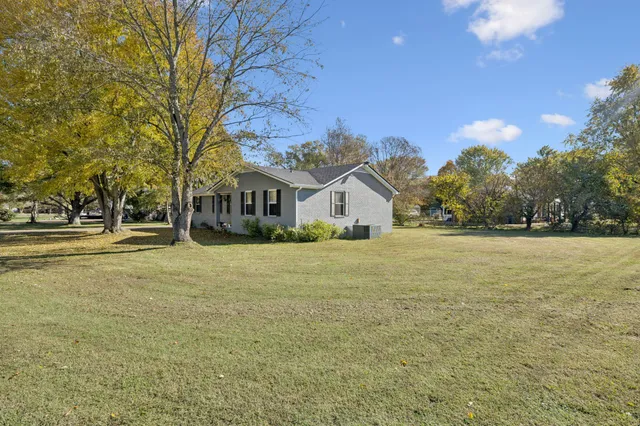 a view of house with outdoor space and trees in the background