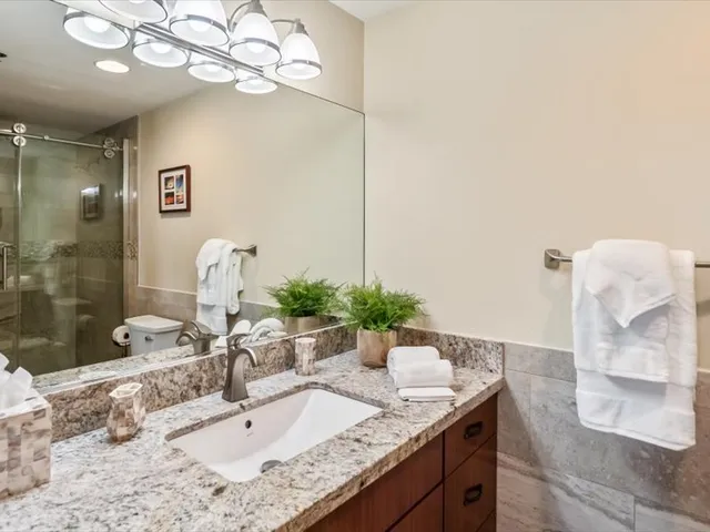 a bathroom with a granite countertop sink a large mirror and shower