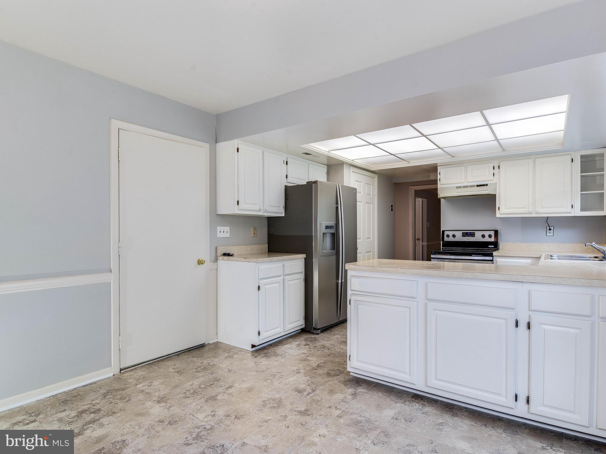13805 Turnmore Road Silver Spring, MD 20906 - Photo 14 of 29 a kitchen with white cabinets and refrigerator