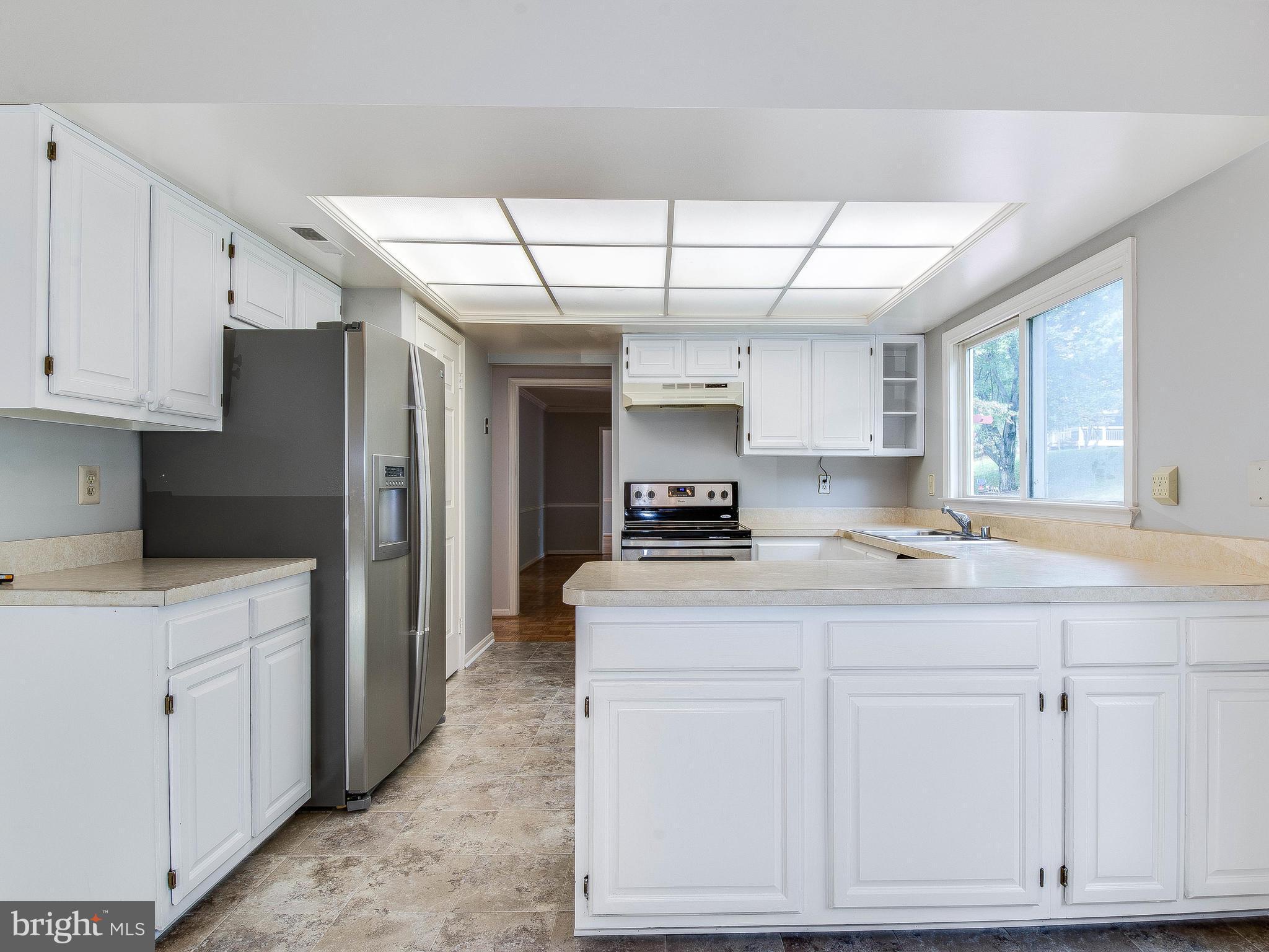 13805 Turnmore Road Silver Spring, MD 20906 - Photo 15 of 29 a kitchen with kitchen island granite countertop white cabinets and refrigerator
