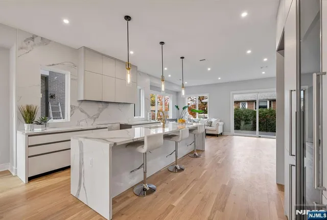 a kitchen with sink stove and white cabinets with wooden floor