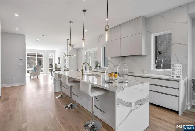 a kitchen with stainless steel appliances kitchen island granite countertop a sink cabinets and wooden floor