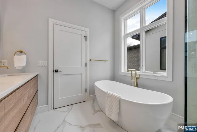 a bathroom with a white tub a mirror and vanity