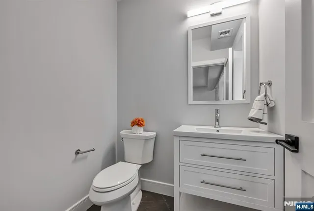 a bathroom with a toilet sink vanity and mirror