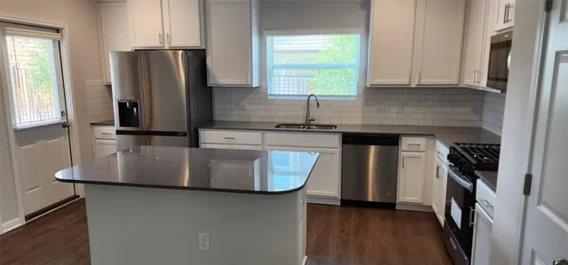 a kitchen with stainless steel appliances granite countertop a refrigerator a sink a stove and a refrigerator