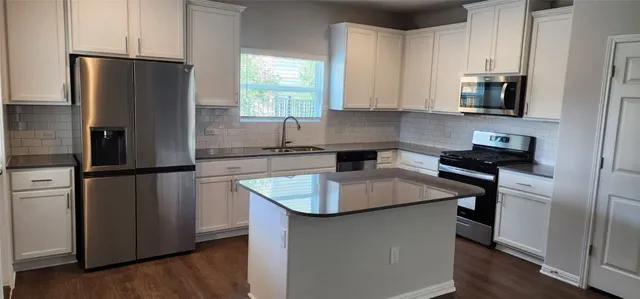 a kitchen with stainless steel appliances granite countertop a refrigerator a sink and a stove