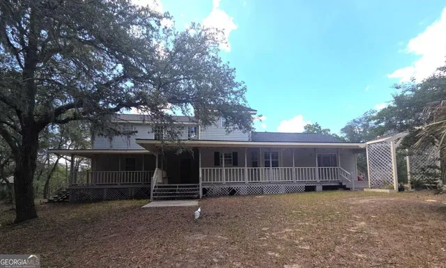 a view of a house with a yard and a large tree