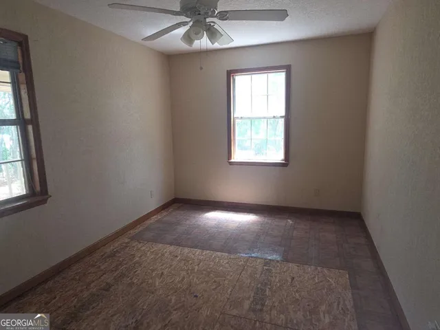 an empty room with a window and a fan