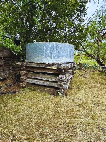 a backyard of a house with large trees and wooden fence