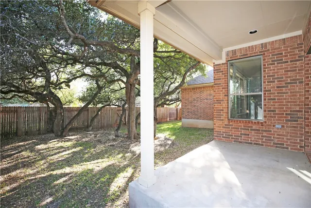 a view of a backyard with large tree and wooden fence