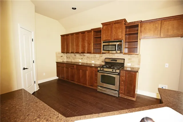 a kitchen with stainless steel appliances granite countertop a stove a sink and a refrigerator