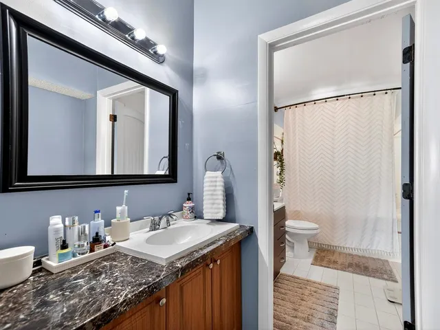 a bathroom with a granite countertop sink a toilet and a mirror
