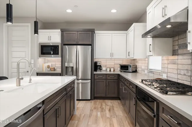 a kitchen with stainless steel appliances granite countertop a sink a stove a refrigerator and island with wooden floor