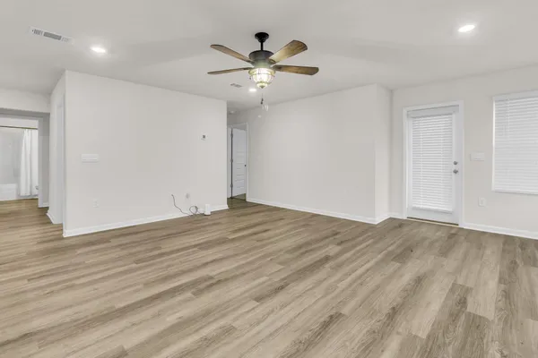an empty room with wooden floor and ceiling fan