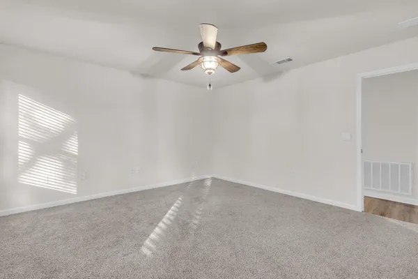 an empty room with windows and fan