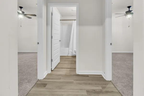 a view of a hallway with wooden floor and a ceiling fan