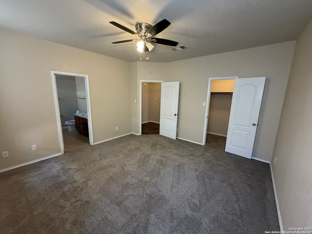 an empty room with closet and a ceiling fan