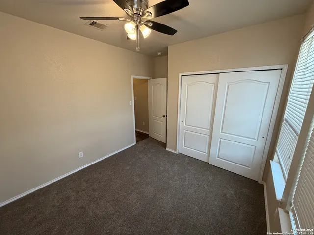 an empty room with closet and a chandelier fan