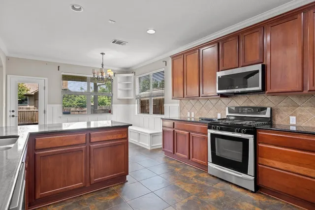 a kitchen with stainless steel appliances granite countertop wooden cabinets and a stove top oven