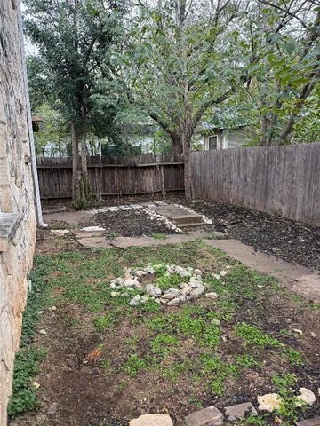 a backyard of a house with large trees and wooden fence