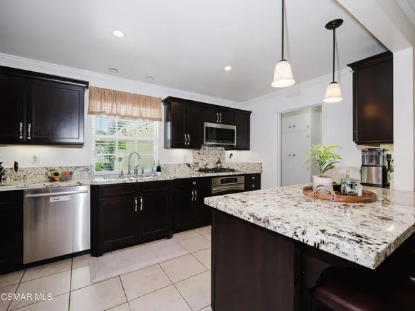 a kitchen with granite countertop stainless steel appliances a sink counter space cabinets and a center island