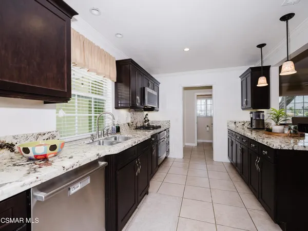 a large kitchen with stainless steel appliances granite countertop a sink counter space cabinets and a large window