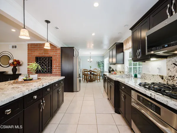 a kitchen with stainless steel appliances kitchen island granite countertop a sink a stove and a wooden cabinets