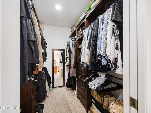 a view of walk in closet with clothes and shoes