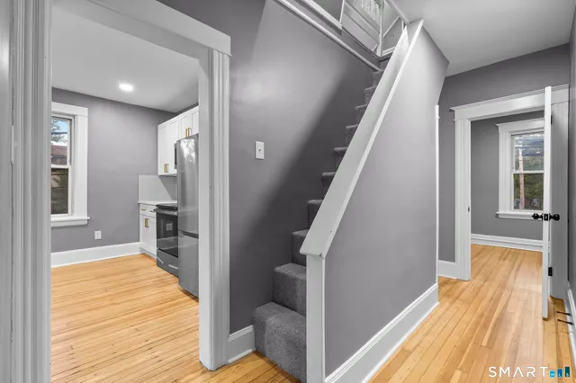 a view of a hallway with wooden floor and staircase