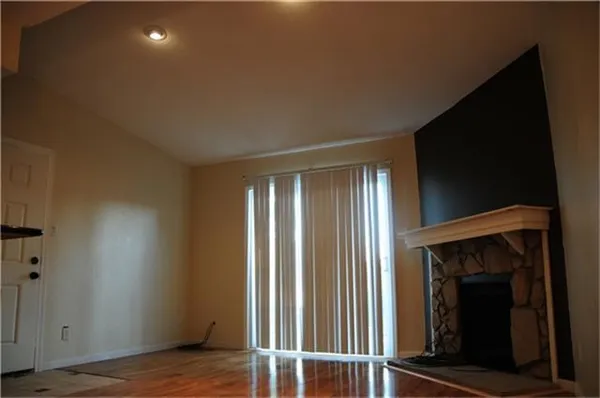 a view of an empty room with wooden floor and a fireplace