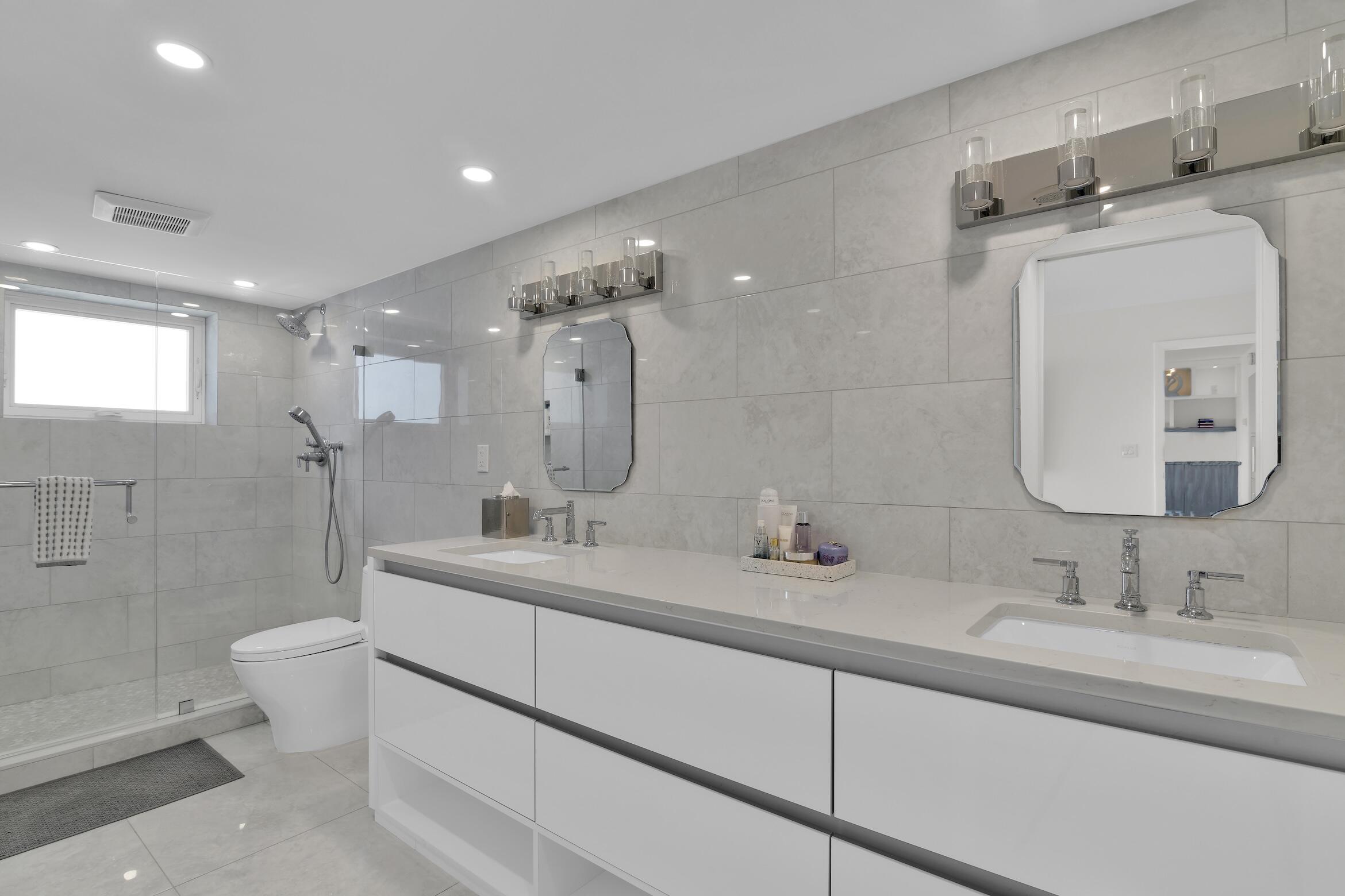 600 South Ocean Boulevard, Unit 802 Boca Raton, FL 33432 - Photo 7 of 27 a bathroom with a double vanity sink toilet mirror and shower