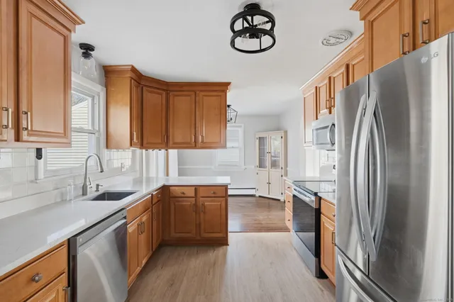 a kitchen with stainless steel appliances granite countertop a refrigerator a sink dishwasher a stove and a sink with wooden floor