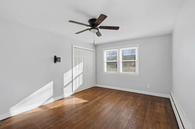 a view of empty room with wooden floor and fan