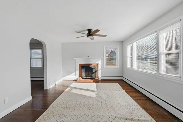 wooden floor in an empty room with a fireplace and a window