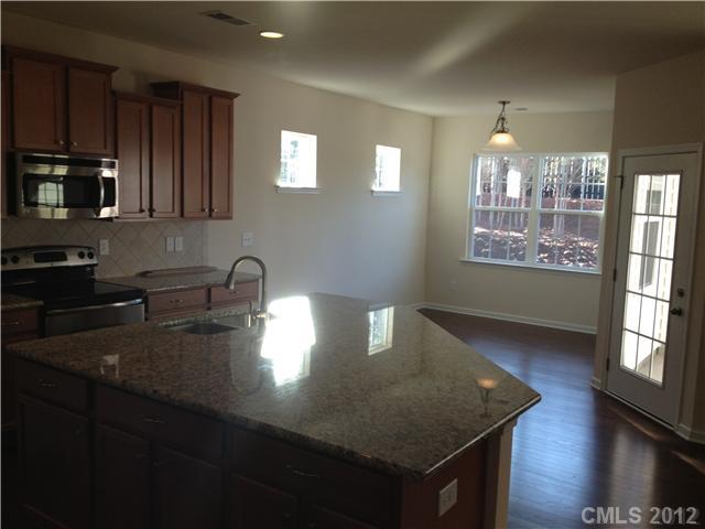 4017 Perth Road, Unit 400 Indian Land, SC 29707 - Photo 4 of 11 a kitchen with kitchen island granite countertop a sink a stove cabinets and wooden floor