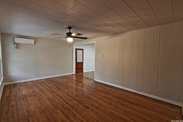 a view of an empty room with wooden floor and a ceiling fan