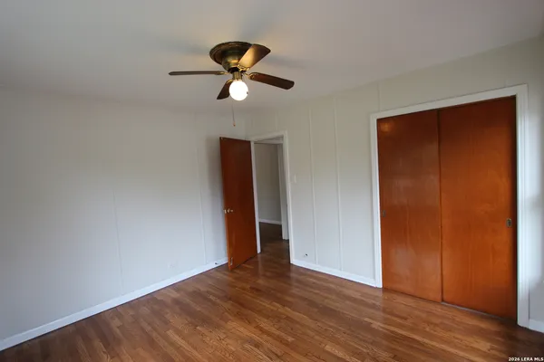 a view of empty room with wooden floor and fan