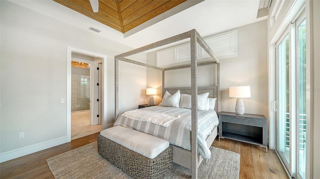 681 Old Compass Road Longboat Key, FL 34228 - Photo 19 of 67 a bedroom with a bed a mirror and a wooden floor