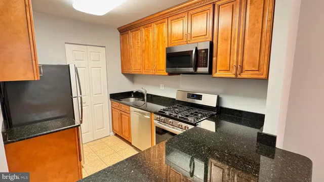 a kitchen with stainless steel appliances granite countertop a stove a sink and a microwave