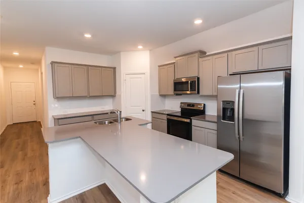 a kitchen with a refrigerator a stove top oven and a sink