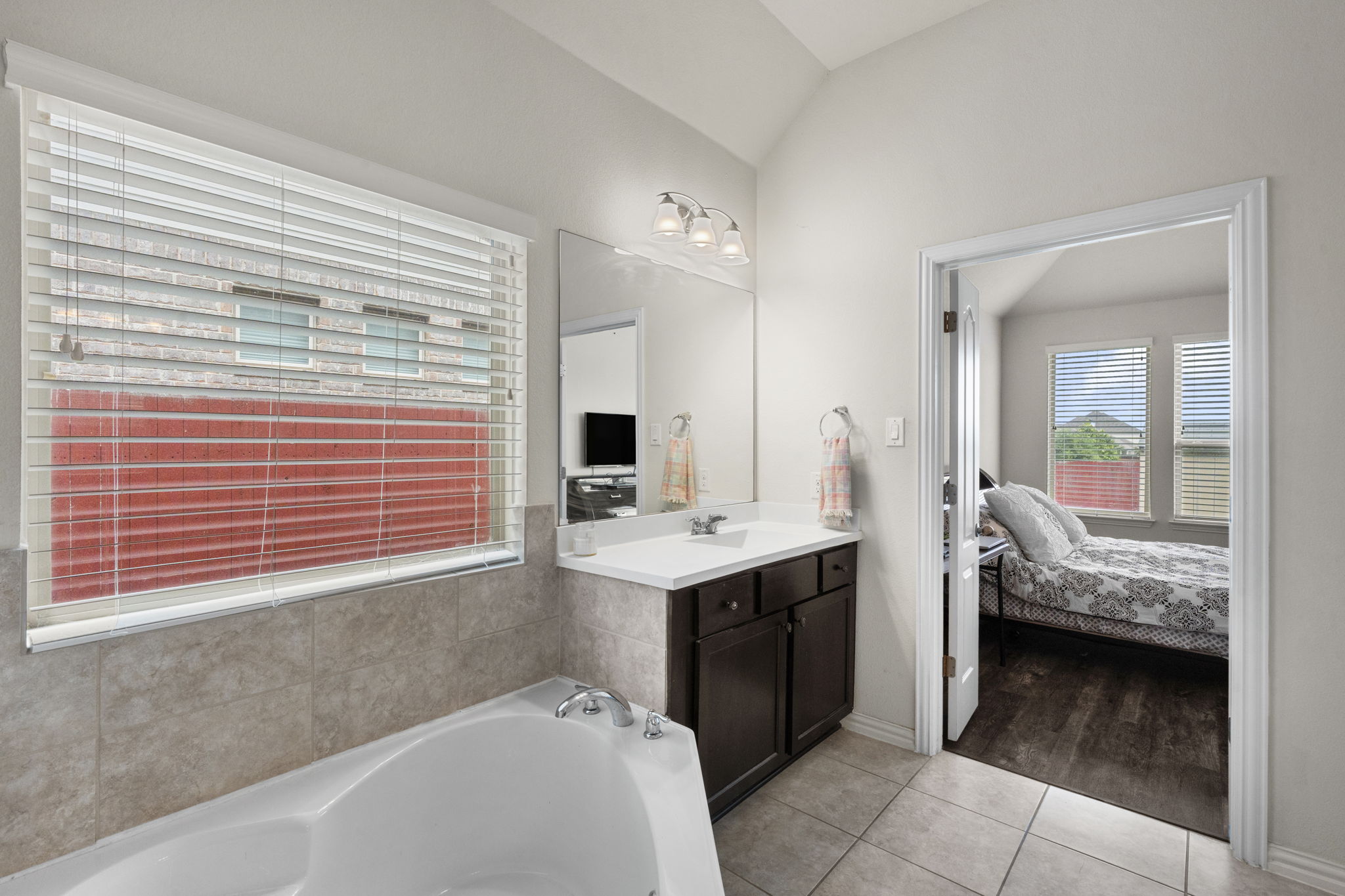 373 Rough Bark Street Buda, TX 78610 - Photo 14 of 39 Indulge in a relaxing soak within this private bath, featuring a generous tub and convenient vanity, seamlessly connected to a restful primary bedroom retreat.