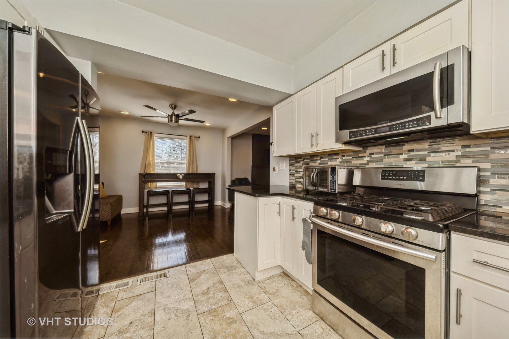 221 Cornwall Drive Crete, IL 60417 - Photo 9 of 26 a kitchen with stainless steel appliances granite countertop a stove top oven a sink dishwasher a dining table and chairs with wooden floor