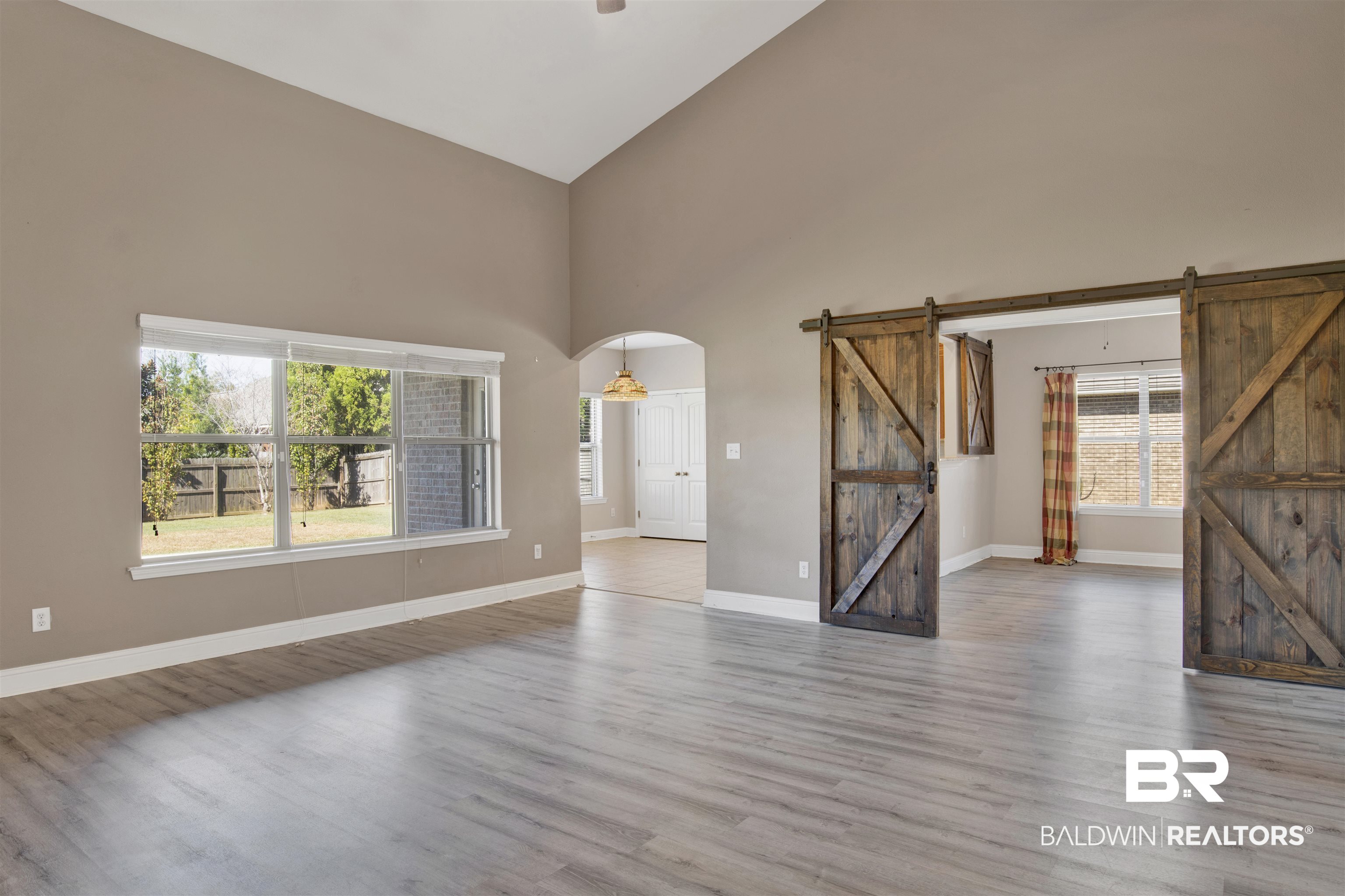 24159 Tullamore Drive Daphne, AL 36526 - Photo 9 of 31 Unfurnished living room with a healthy amount of sunlight, a barn door, and light wood-type flooring